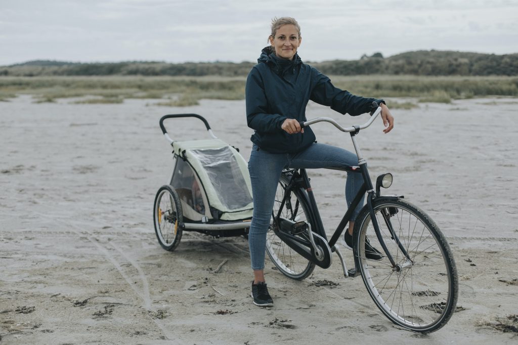 Netherlands, Schiermonnikoog, woman with bicycle and trailer on the beach