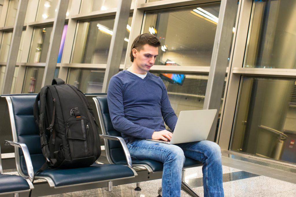 Young man with laptop and backpack at airport