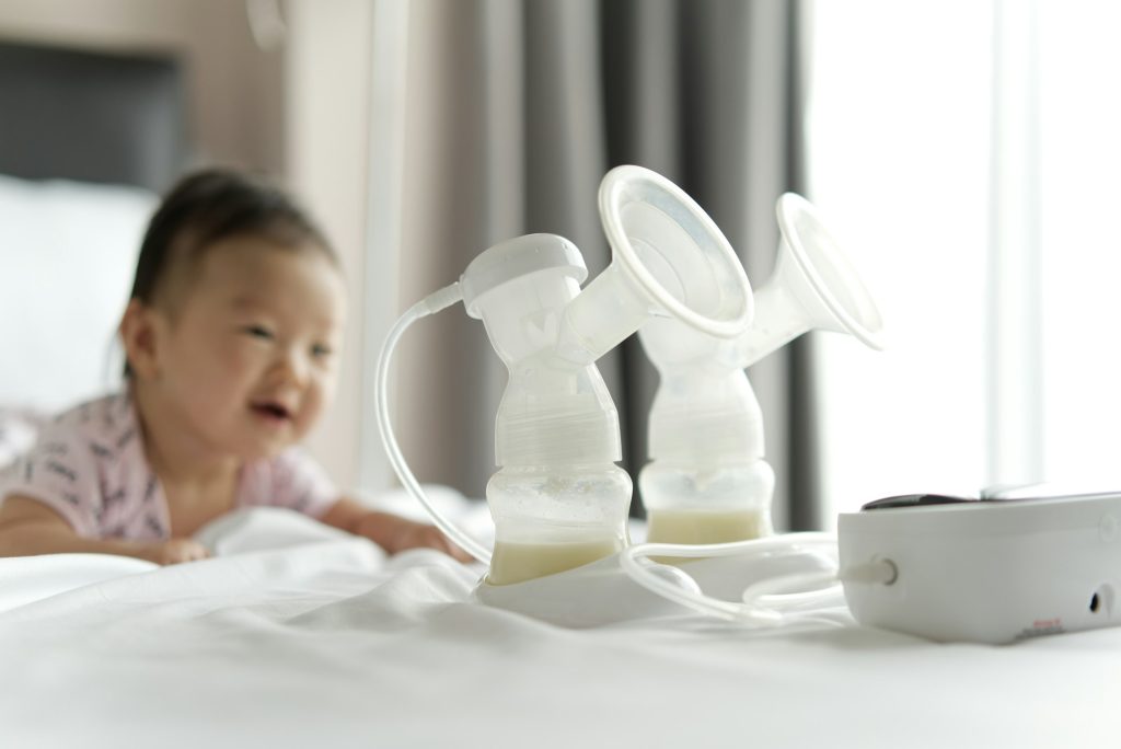 Breast milk in milk pump's bottles and pump machine on the bed.